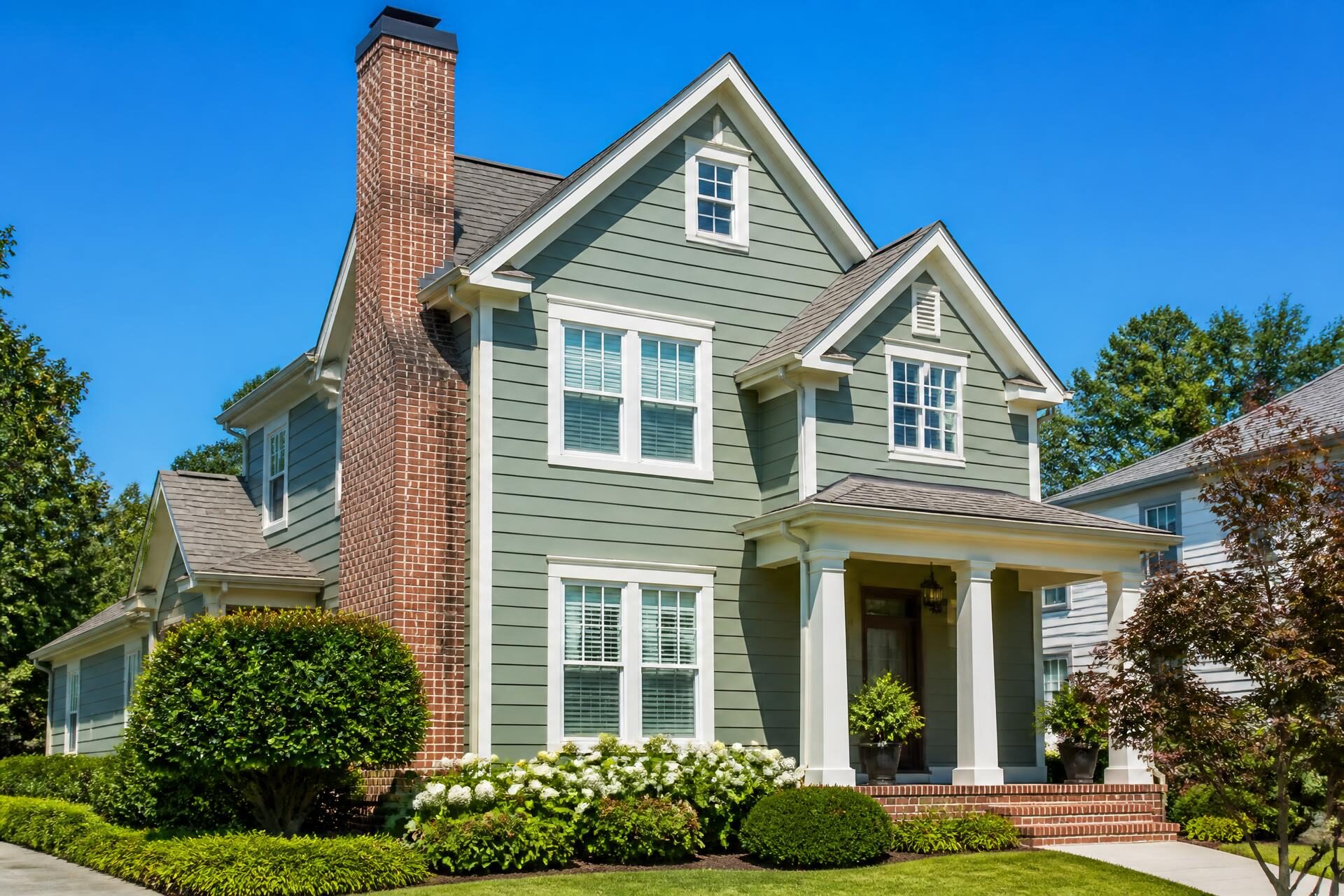 Suburban home with a tall brick chimney under a bright blue sky in Rye Brook, New York